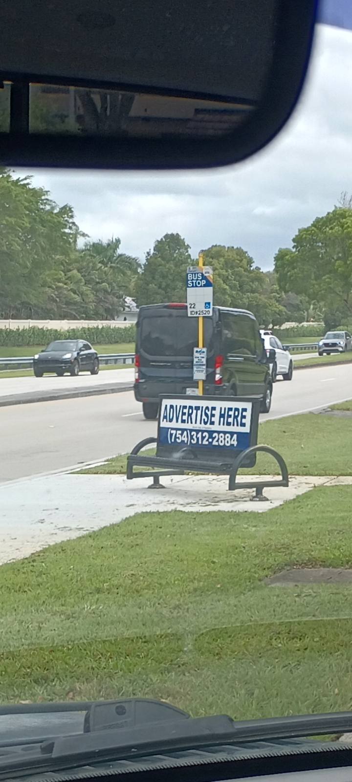Bus bench showing Advertise Here phone number on Broward Boulevard